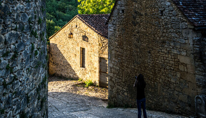Una mujer joven hace fotos de una calle en una aldea medieval francesa © Franjagoher