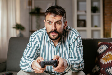 Fototapeta na wymiar Young attractive man playing video games in the living room. Handsome man having fun at home