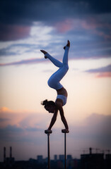 Flexible female circus Artis keep balance and doing contortion on the rooftop against dramatic...