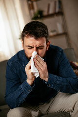 Sick man at home. Young man sitting on sofa having virus