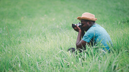 Naklejka na ściany i meble African man traveler take photo among green meadows field.16:9 style