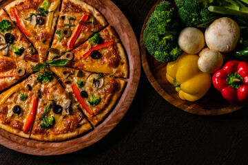 Beautiful photography from top view of yummy pizza with colorful vegetables on black surface.