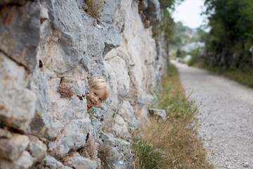 Child, toddler boy, hiding between the rocks in a mountains, hiking