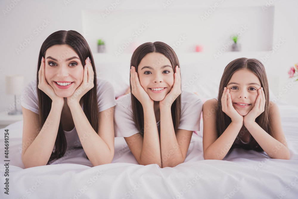 Sticker Photo of dreamy pretty three siblings nightwear lying bed arms cheeks smiling indoors inside room home