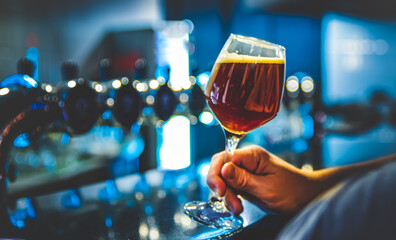 man holds a glass of beer in his hand at the bar or pub