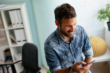 Businessman in office using the phone. Young man typing a message.