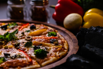 Close up shot of yummy pizza along with vegetables and coal on wooden surface.