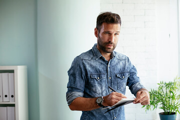 Fototapeta premium Handsome businessman sitting on a desk, writing notes. Businessman making businessplan..