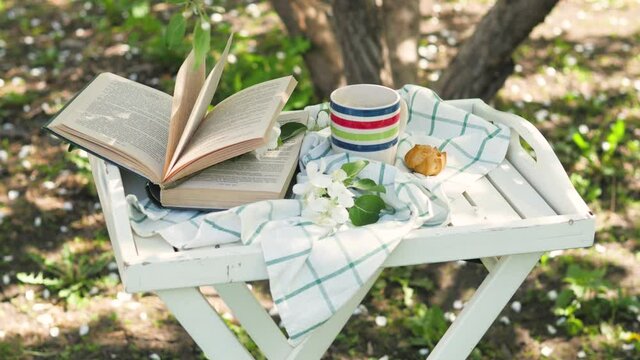 Novosibirsk, 05.12.2020. composition with a cup of tea with a plaid and a book on a small white table on a wood background. breakfast in nature