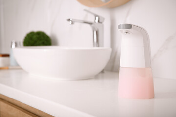 Fototapeta na wymiar Modern automatic soap dispenser on countertop in bathroom