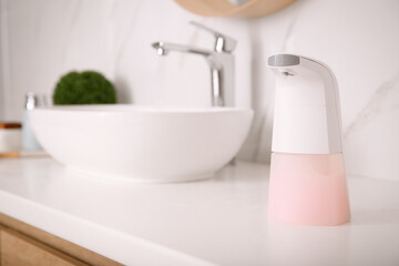 Modern automatic soap dispenser on countertop in bathroom