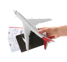 Woman holding toy airplane, passport and tickets on white background, closeup