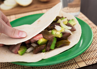 salad of black tomatoes, avocado and onions in Italian tortilla on green plate