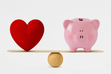 Heart and piggy bank on balance scale - Balance between love and money - 414696564