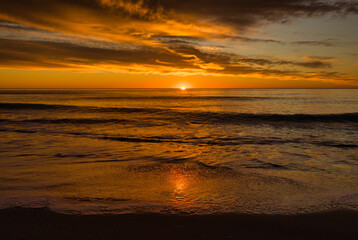 Naklejka na ściany i meble A beautiful sunrise from the shore of the beach