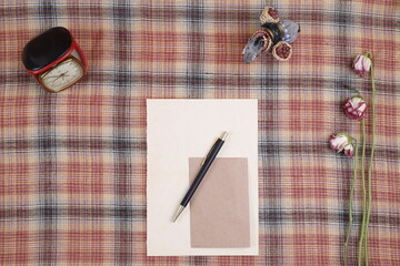 Kartka papieru stara i długopis czarny na obrusie brązowym kraciastym