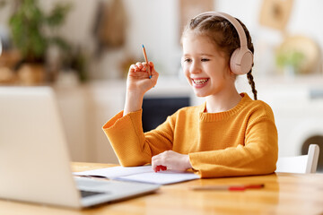 Happy girl having online lesson via laptop at home