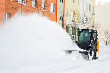 small tractor cleans snow from the street