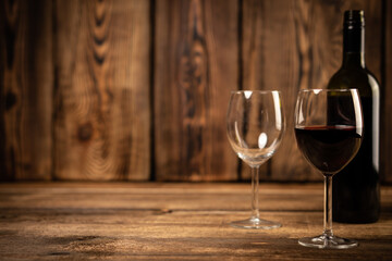 Red wine glasses and bottle red wine on old wooden background.