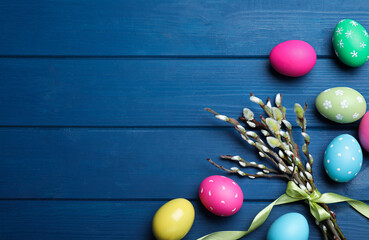 Bright painted eggs and pussy willows on blue wooden table, flat lay with space for text. Happy Easter © New Africa