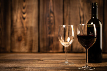 Red wine glasses and bottle red wine on old wooden background.