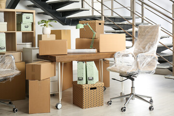 Fototapeta na wymiar Cardboard boxes and furniture near stairs in office. Moving day