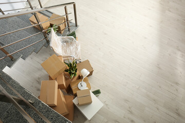 Cardboard boxes and packed chair near stairs in office, above view with space for text. Moving day