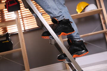 Person climbing ladder indoors, closeup on feet © New Africa