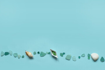 Paper ship, sea shell and stones isolated on blue background. Sea and vacation concept.