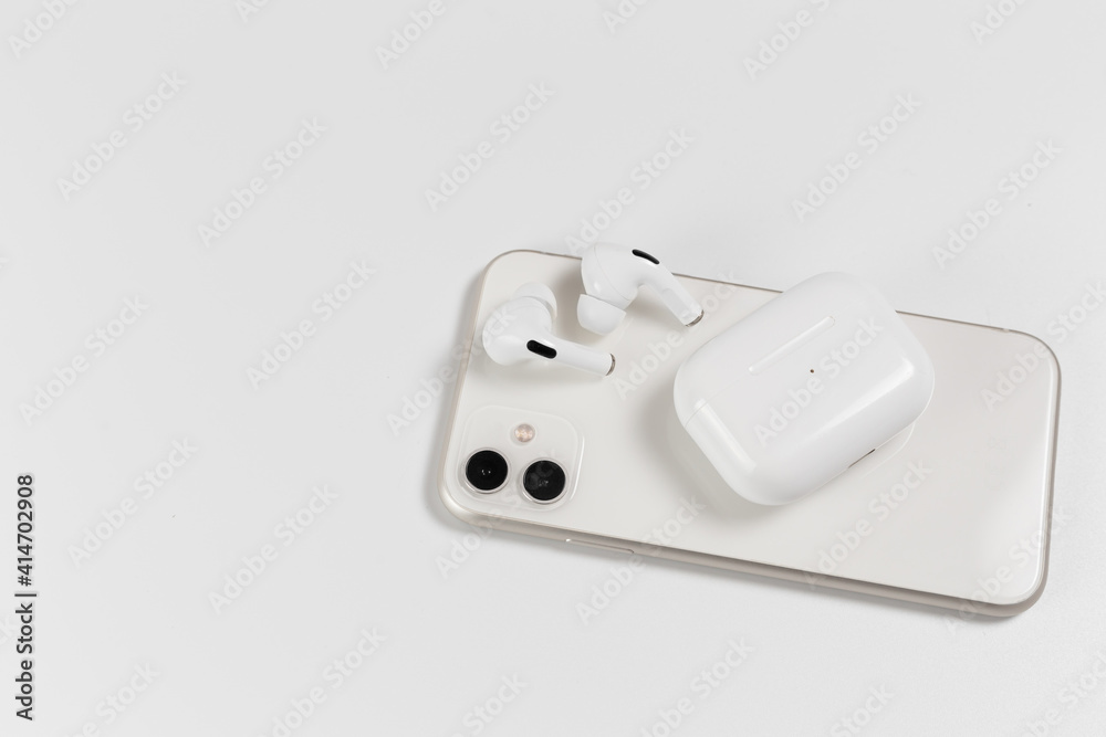 Wall mural white wireless headphones on a white background. white smartphone