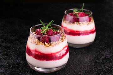 Yogurt with raspberries and granola on a black background.