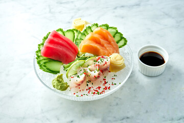 Classic Japanese sashimi set of raw salmon, eel and tuna with lime, cucumber on plate on a marble background. Close up, selective focus