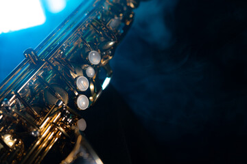 Golden shiny alto saxophone on black background with blue smoke