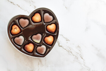 Top view of chocolate candy heart box on white marble background with copy space