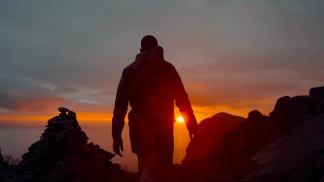 SLOW MOTION: walking to cliff on top of mountain during sunset in Lofoten Islands, Norway