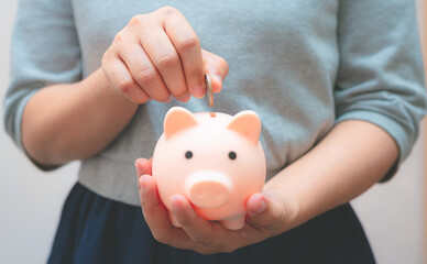 business woman hold piggy bank and putting coin with concrete wall for financial and saving money...