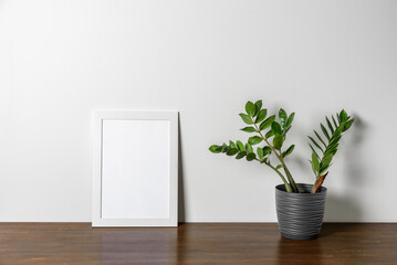 White wooden Photo or poster frame mock up on table with home plant. Minimal