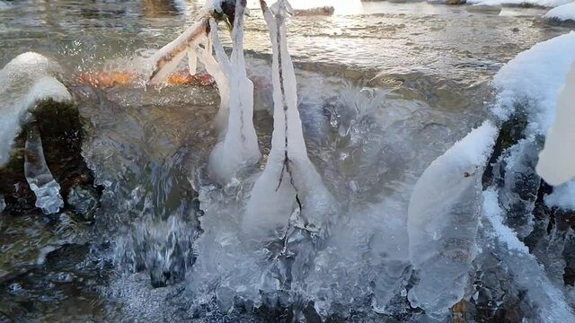 Eiszapfen an &Auml;sten an einem Kristallklarem Bergbach
