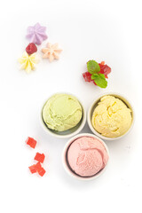 Strawberry, pistachio and lemon ice cream balls in a bowl, isolated on a white background. Top view