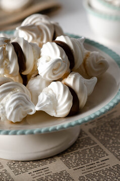 Meringue Cookies With Dulce De Leche On A White And Green Cake Stand On An Old Magazine And Some Tea Cups In The Background. 