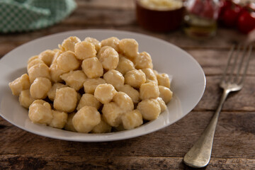 Gnocchi without sauce on a white plate and rustic wood