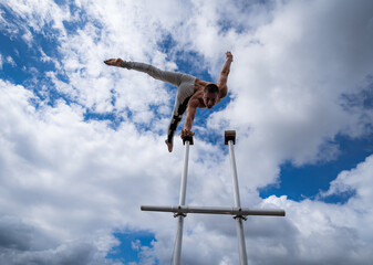 Flexible male circus Artist keep balance by one hand on the rooftop against amazing cloudscape. Motivation, passion and achievement concept 