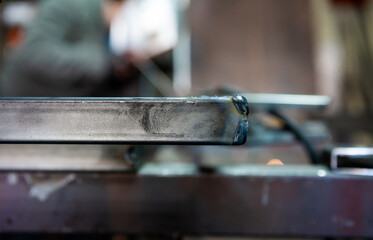 The focus is on the welding pipe, and behind it is the worker who welds the pipes in the old workshop.