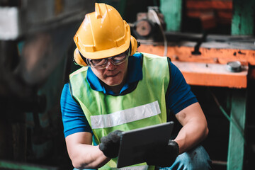 Work at factory.Asian worker man  working in safety work wear with yellow helmet using digital tablet .in factory workshop industry machine professional © BigBlues