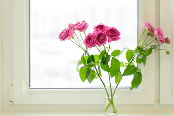 a bouquet of pink roses by the window on a winter day