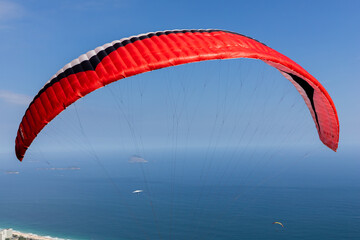 Red, blue and white paragliding canvas flying against a blue sky