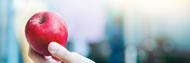 Young Girl hand holding Red Apple on beautiful blur Background.