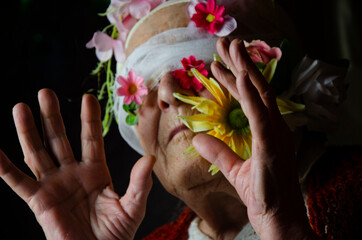 A blindfolded grandmother in the dark. A bandage with flowers on the eyes of an old grandmother....