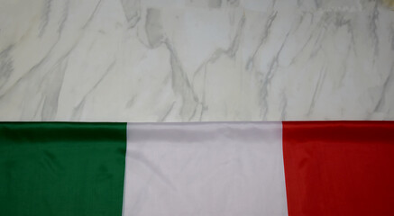 Italy flag on marble background, top view, place for your text. The Italian flag lies on a marble slab. National holiday concept. Italy national flag background with fabric texture.