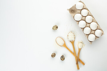 Eggs and quail eggs and sugar, coconut shavings in wooden spoons 